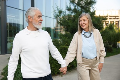 Photo of Lovely senior couple walking together near building outdoors
