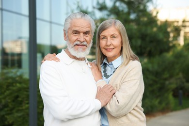 Photo of Lovely senior couple walking together near building outdoors