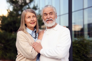 Photo of Lovely senior couple walking together near building outdoors