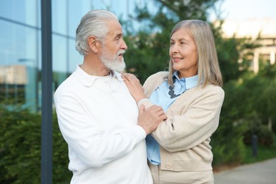 Photo of Lovely senior couple walking together near building outdoors