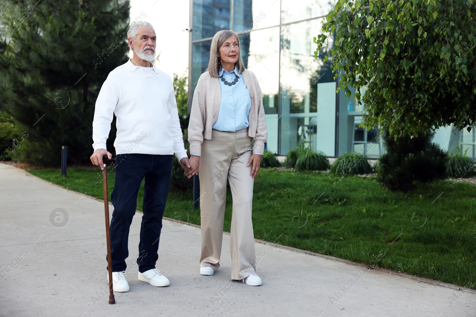 Lovely senior couple walking together near building outdoors, space for text Photo of Lovely senior couple walking together near building outdoors, space for text