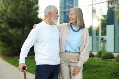 Photo of Lovely senior couple walking together near building outdoors
