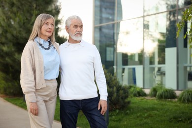 Photo of Lovely senior couple walking together near building outdoors, space for text