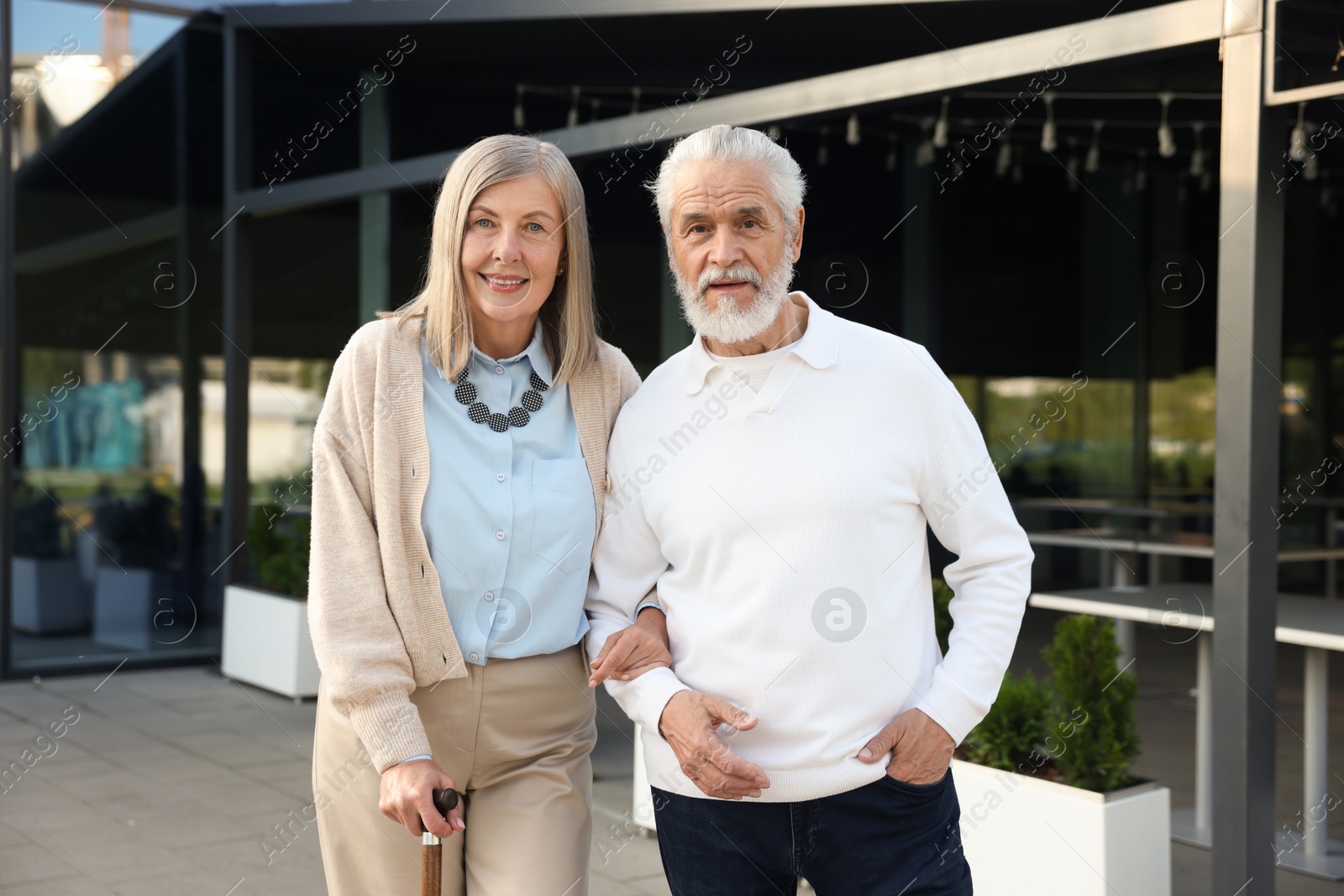 Lovely senior couple walking together near outdoor cafe Photo of Lovely senior couple walking together near outdoor cafe