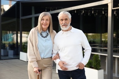 Photo of Lovely senior couple walking together near outdoor cafe