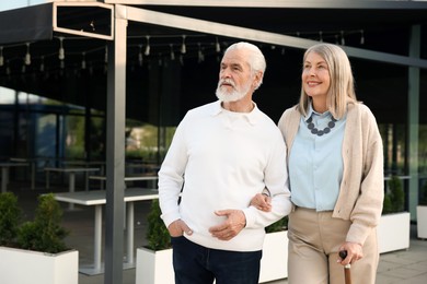 Photo of Lovely senior couple walking together near outdoor cafe, space for text