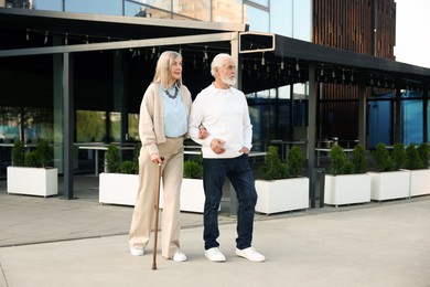 Photo of Lovely senior couple walking together near outdoor cafe