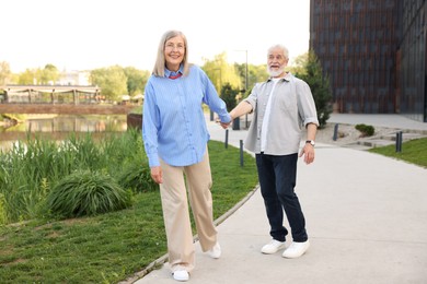 Photo of Lovely senior couple walking together in park