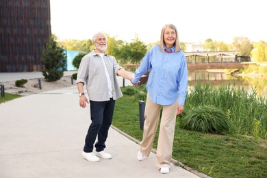 Photo of Lovely senior couple walking together in park