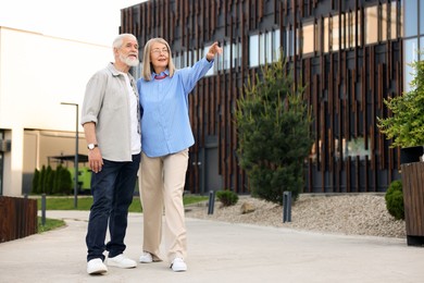Photo of Lovely senior couple walking together in park, space for text