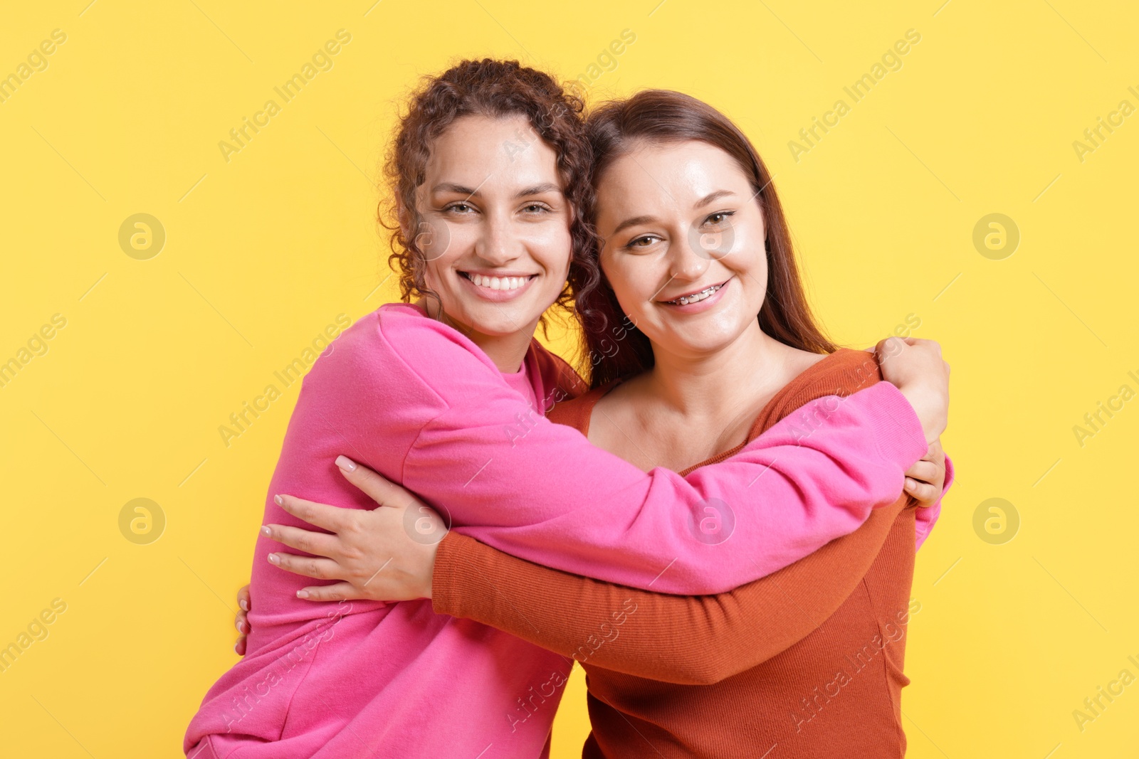 Friends hugging each other on orange background Photo of Friends hugging each other on orange background