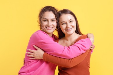 Photo of Friends hugging each other on orange background