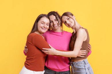 Photo of Friends hugging each other on orange background