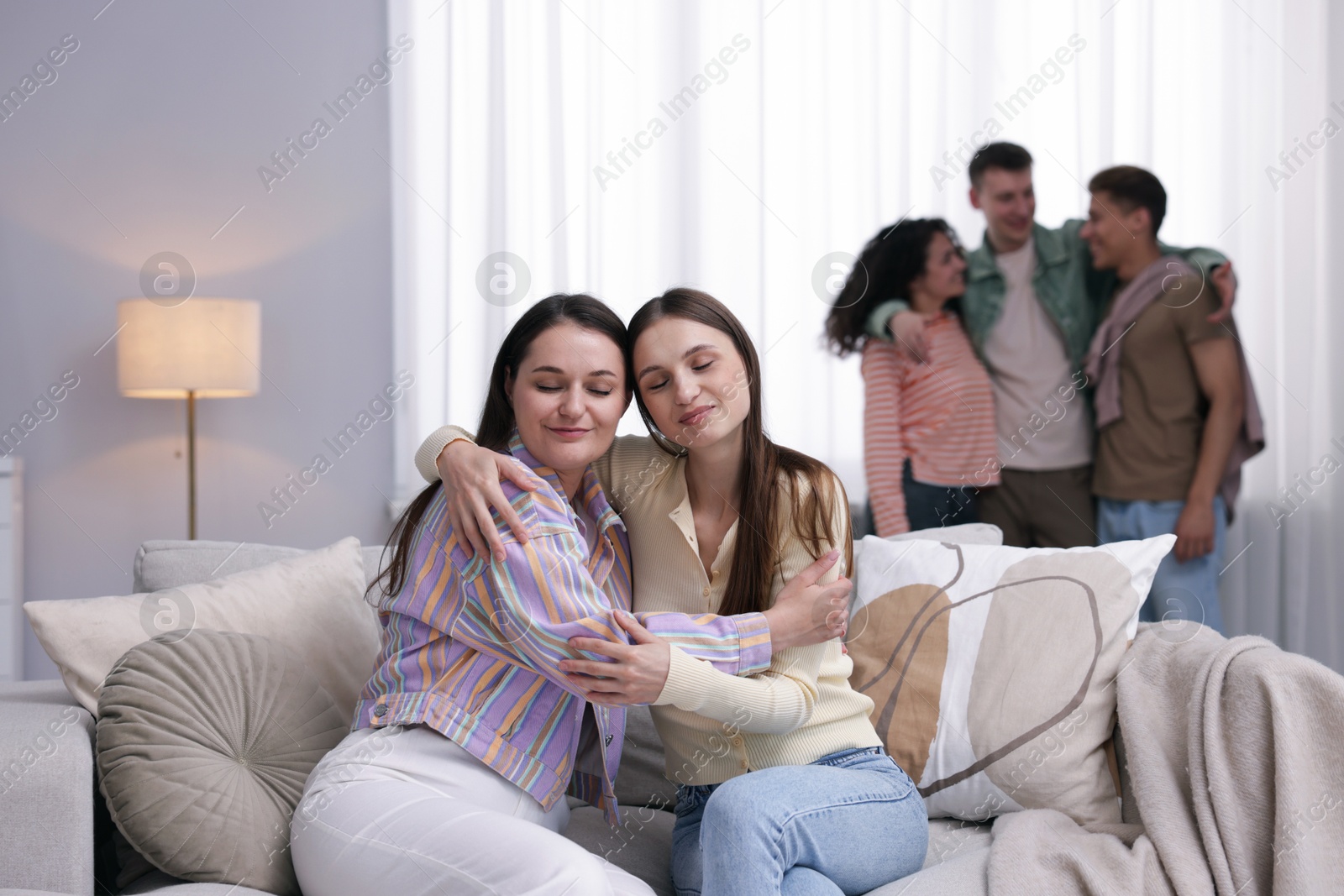 Friends hugging on sofa indoors, selective focus Photo of Friends hugging on sofa indoors, selective focus