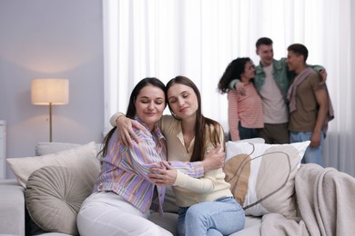 Photo of Friends hugging on sofa indoors, selective focus