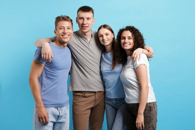 Photo of Group of friends hugging on light blue background