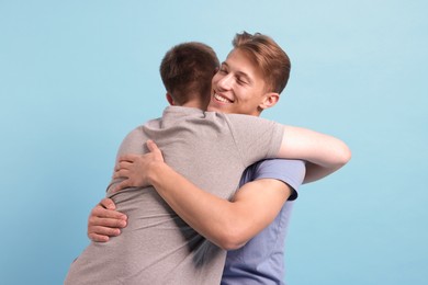 Photo of Two friends hugging on light blue background