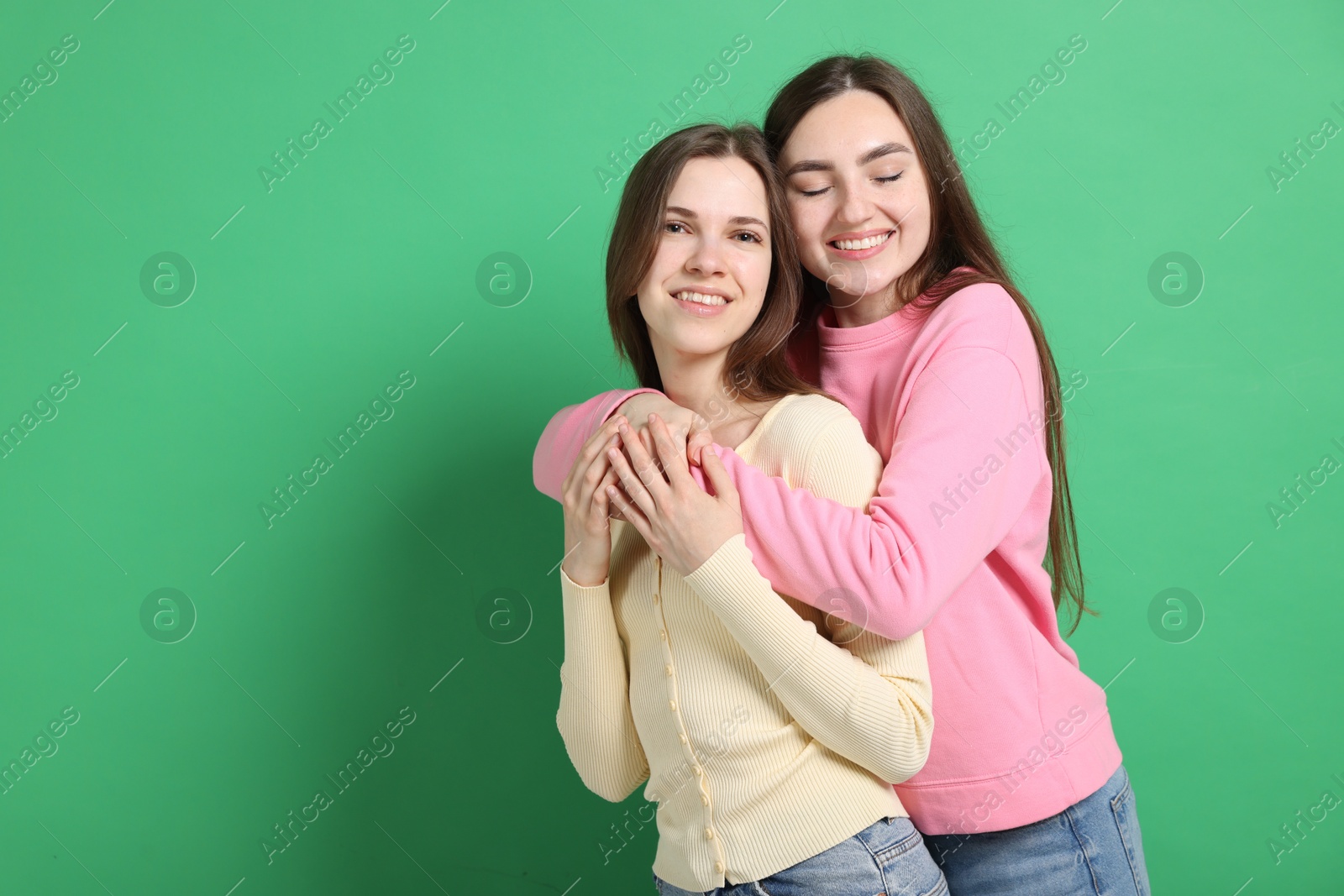 Happy friends hugging each other on green background, space for text Photo of Happy friends hugging each other on green background, space for text