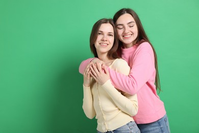 Photo of Happy friends hugging each other on green background, space for text