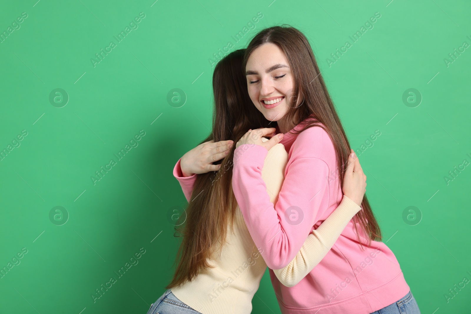 Friends hugging each other on green background, space for text Photo of Friends hugging each other on green background, space for text