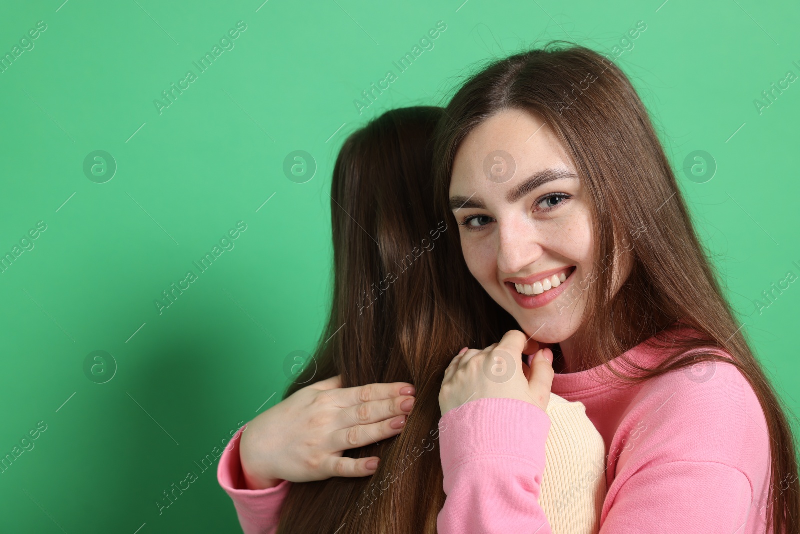 Friends hugging each other on green background, space for text Photo of Friends hugging each other on green background, space for text