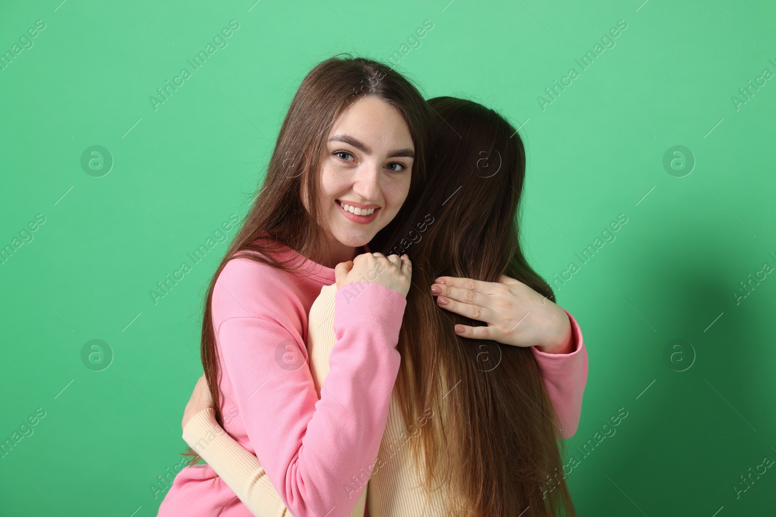 Friends hugging each other on green background Photo of Friends hugging each other on green background