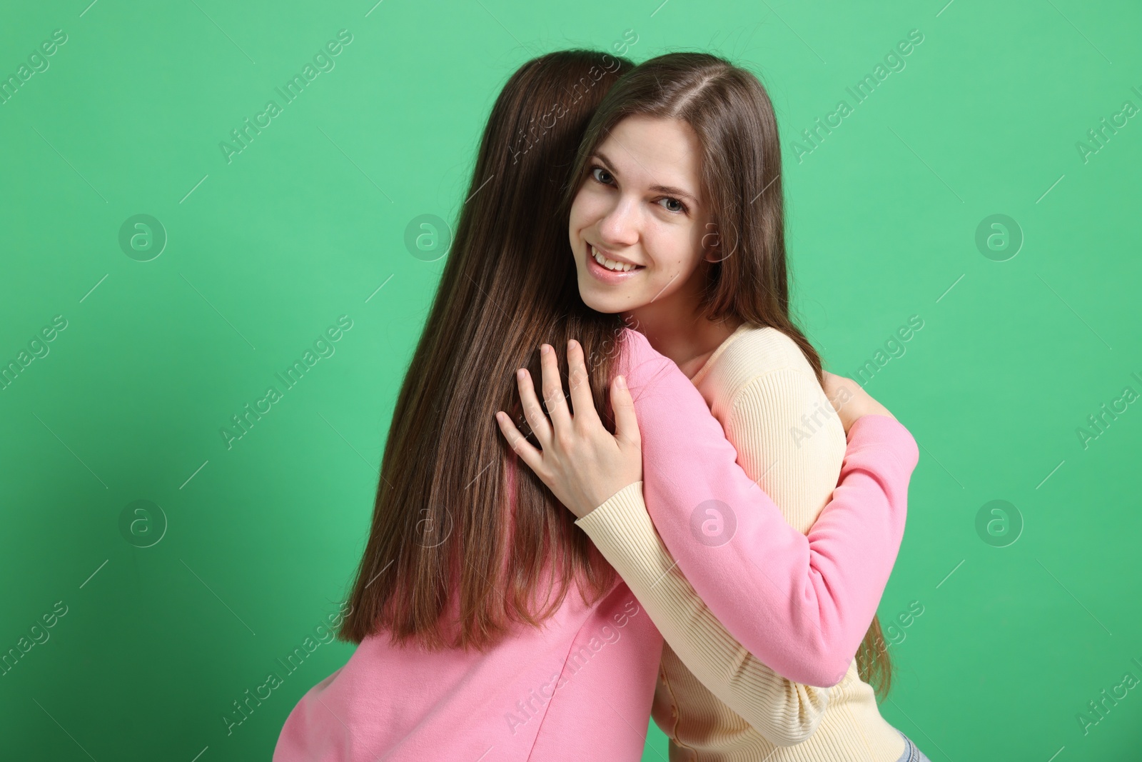 Friends hugging each other on green background Photo of Friends hugging each other on green background