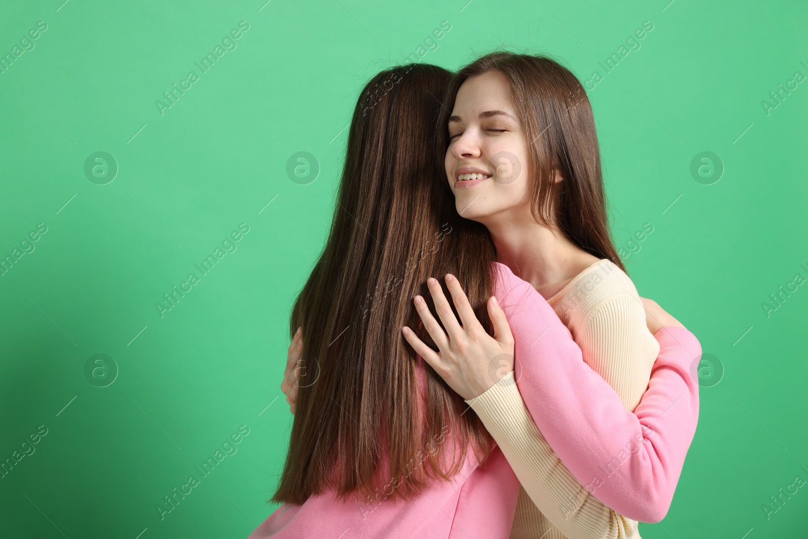 Friends hugging each other on green background, space for text Photo of Friends hugging each other on green background, space for text