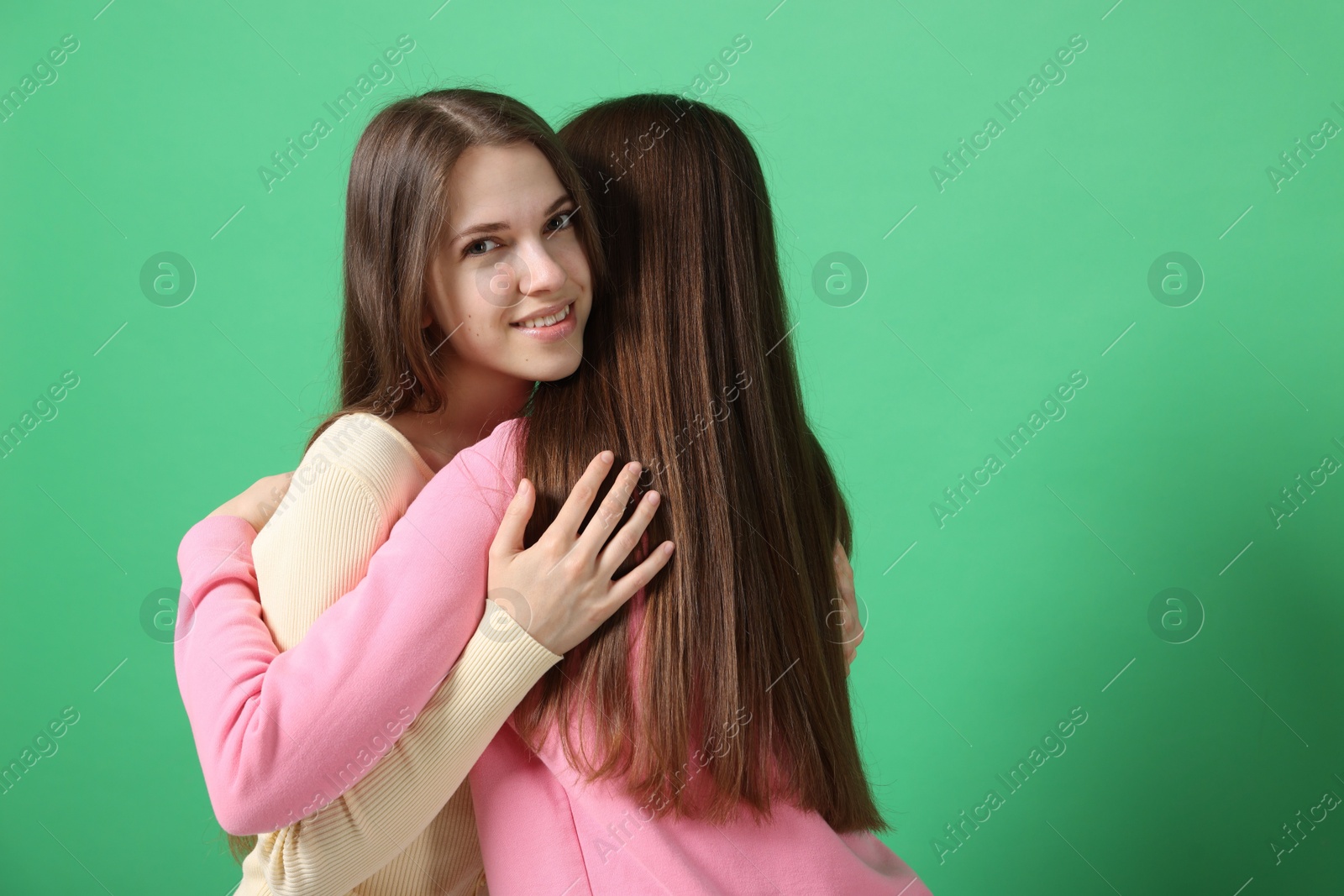 Friends hugging each other on green background, space for text Photo of Friends hugging each other on green background, space for text
