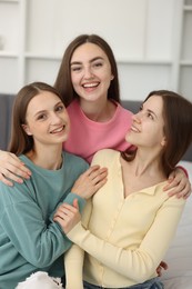 Photo of Happy friends hugging each other on bed at home
