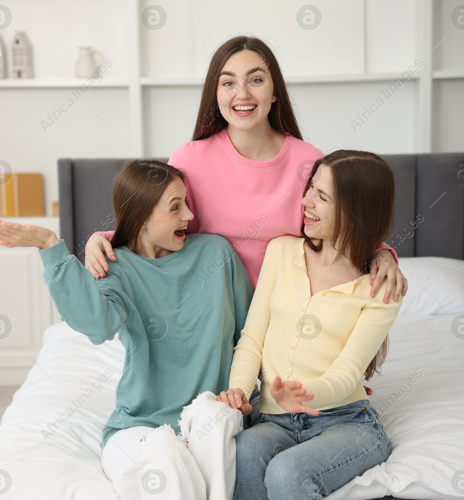 Happy friends hugging each other on bed at home Photo of Happy friends hugging each other on bed at home
