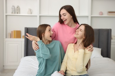 Photo of Happy friends hugging each other on bed at home