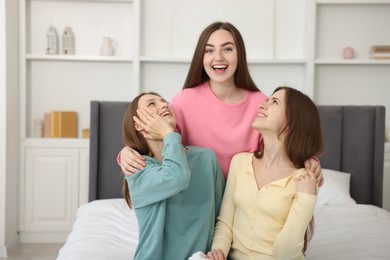 Photo of Happy friends hugging each other on bed at home