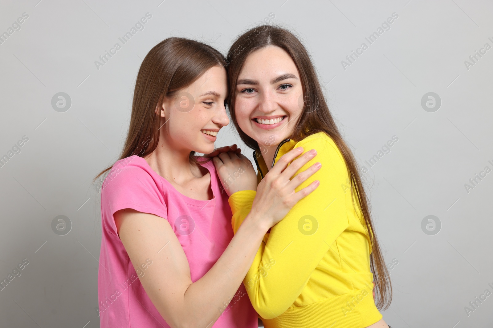 Friends hugging each other on light grey background Photo of Friends hugging each other on light grey background