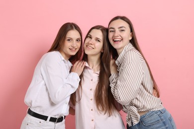 Photo of Friends hugging each other on pink background