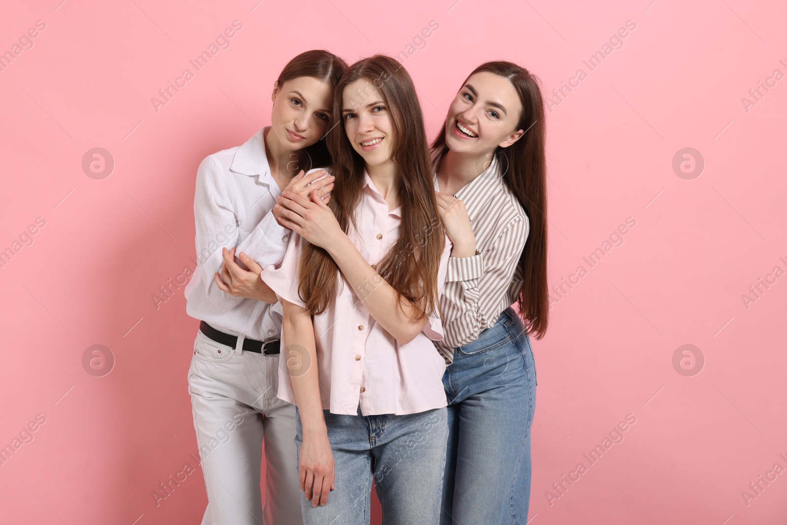 Friends hugging each other on pink background Photo of Friends hugging each other on pink background