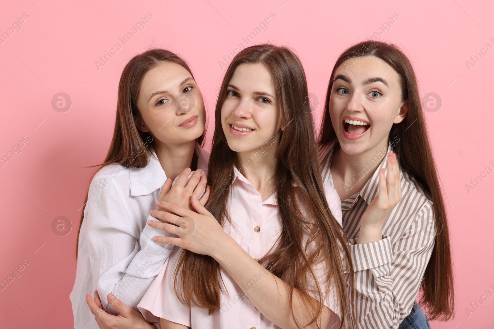 Friends hugging each other on pink background Photo of Friends hugging each other on pink background