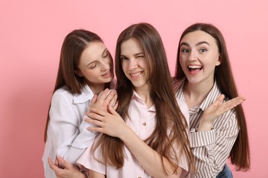 Photo of Friends hugging each other on pink background