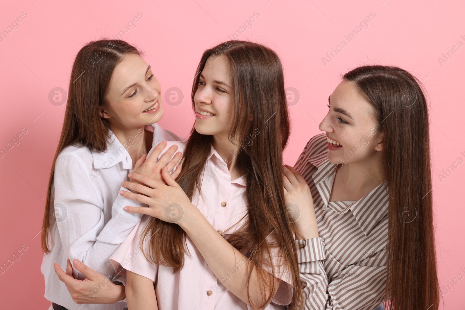 Friends hugging each other on pink background Photo of Friends hugging each other on pink background
