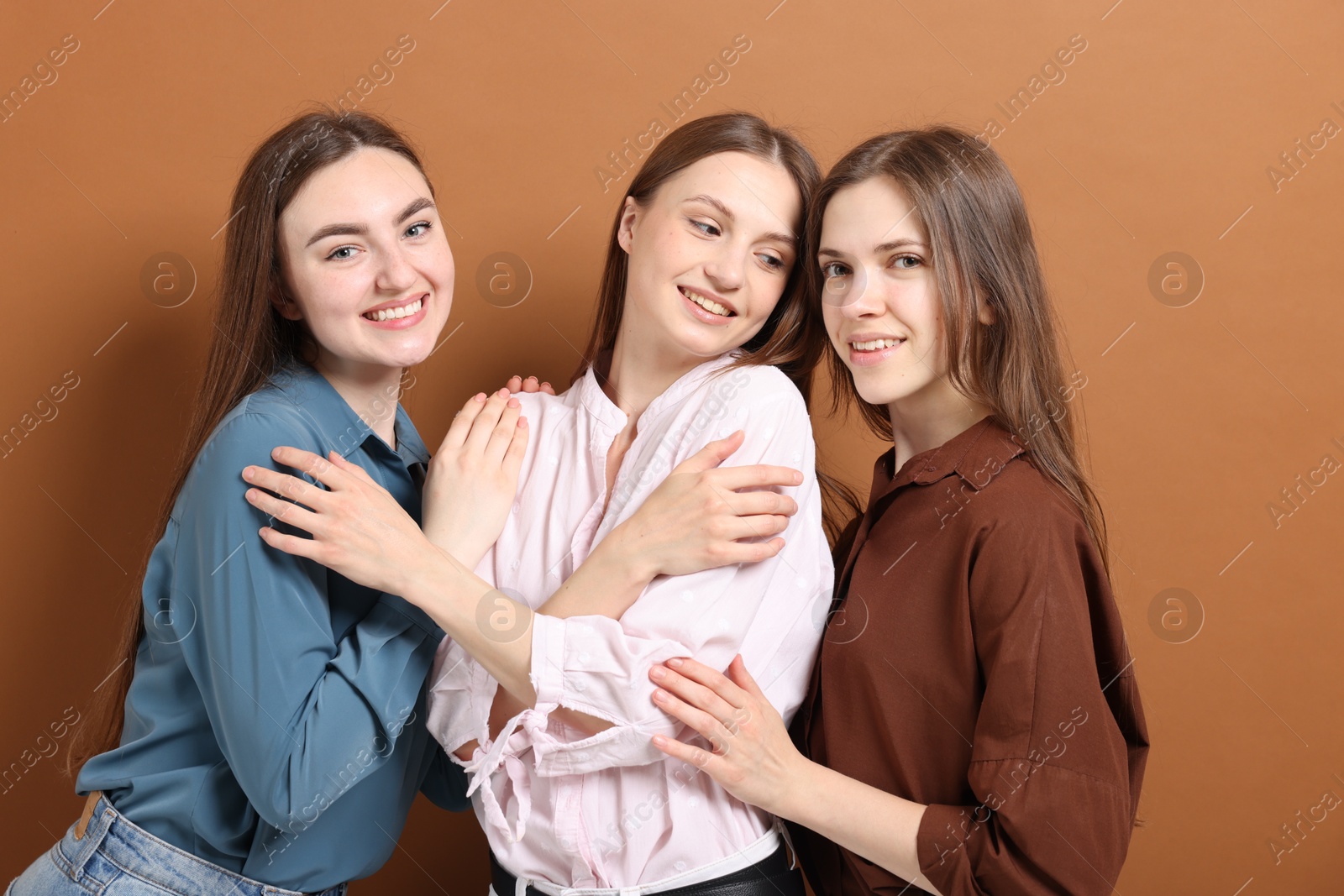 Friends hugging each other on pale brown background Photo of Friends hugging each other on pale brown background
