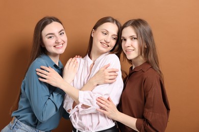 Photo of Friends hugging each other on pale brown background