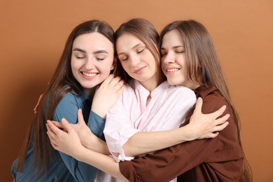 Photo of Friends hugging each other on pale brown background