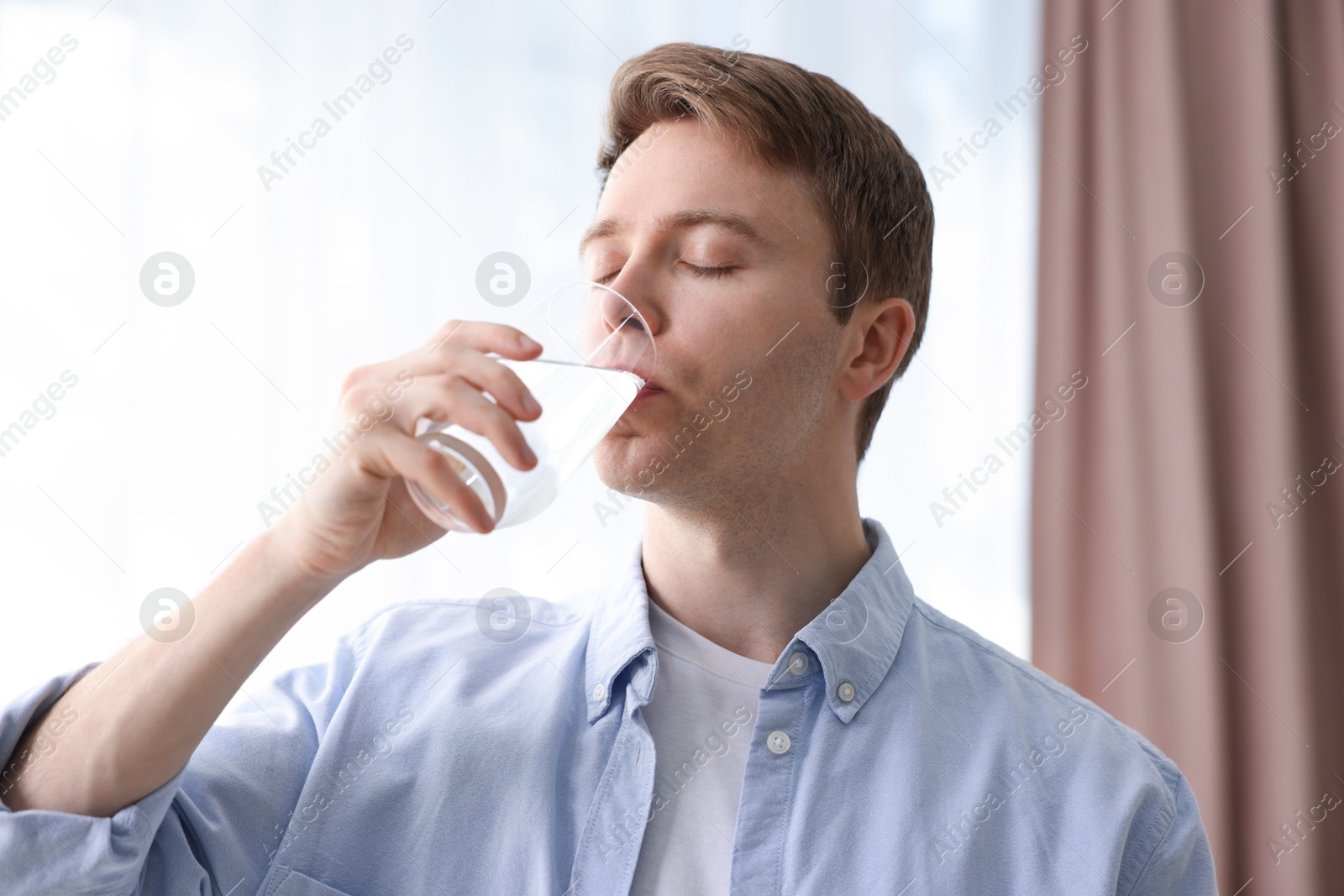 Man drinking water from glass at home Photo of Man drinking water from glass at home