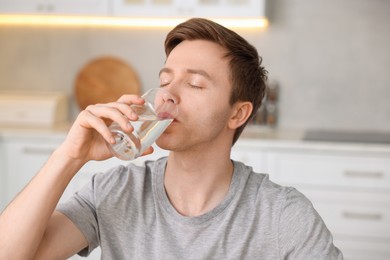 Photo of Man drinking water from glass in kitchen