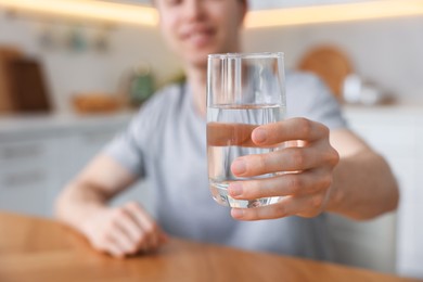 Photo of Man with glass of water in kitchen, selective focus
