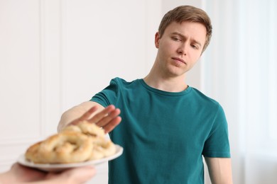 Photo of Gluten free diet. Man refusing from pastries indoors, selective focus