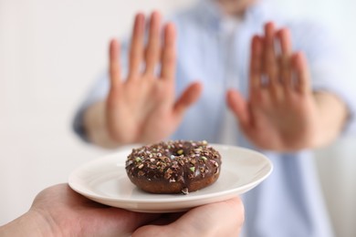 Photo of Gluten free diet. Man refusing from donut indoors, selective focus