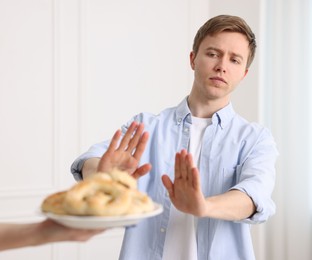 Photo of Gluten free diet. Man refusing from pastries indoors, selective focus