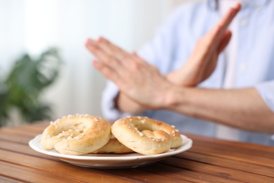 Photo of Gluten free diet. Man refusing from pastries at wooden table indoors, selective focus