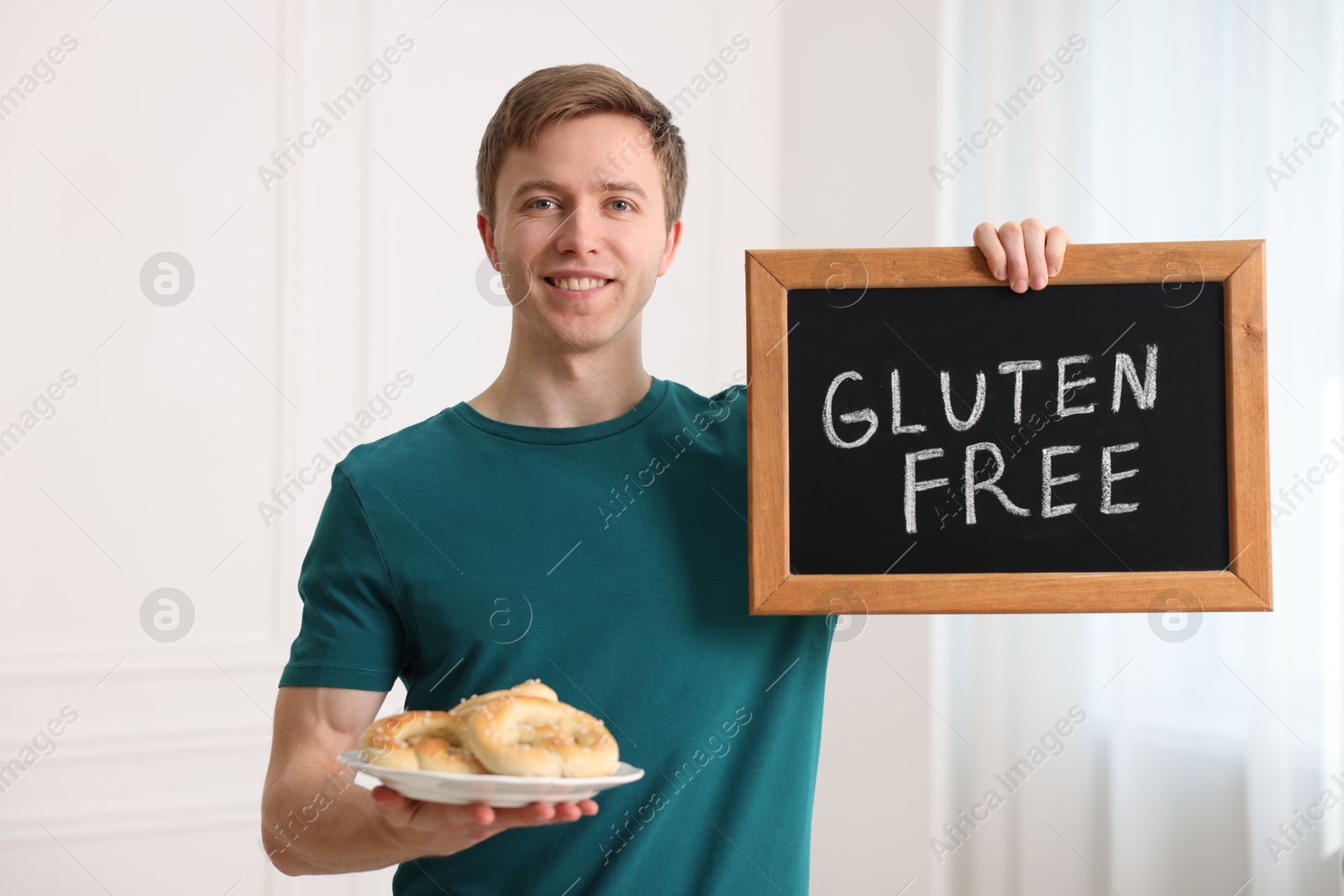 Man holding small chalkboard with text Gluten Free and pretzels indoors Photo of Man holding small chalkboard with text Gluten Free and pretzels indoors